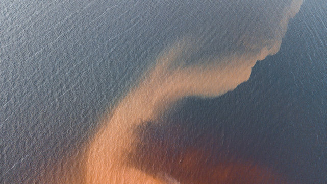 Aerial view of the sandy waves diffusing in the water