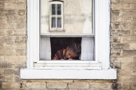 Portrait of young child sitting and writing in front of an old textured window