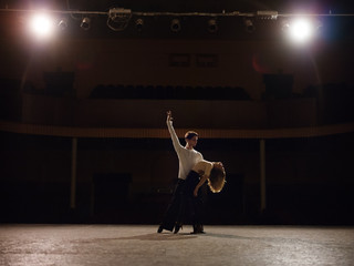Beautiful couple performing dance on illuminated stage