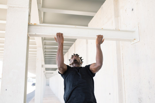 Black man doing chin-ups on street