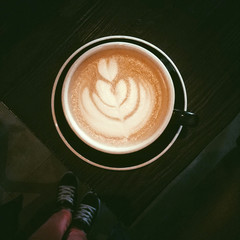 Closeup cup of coffee cappuccino with latte-art image on wooden table. Top view.