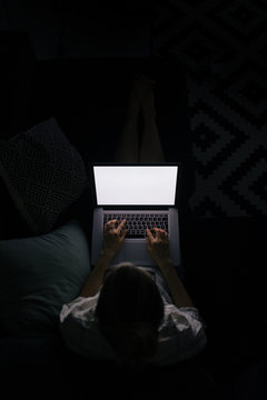 young woman with laptop on the sofa at night