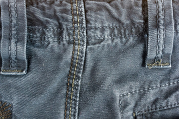 clothing items stonewashed cotton fabric texture with seams, clasps, buttons and rivets, macro