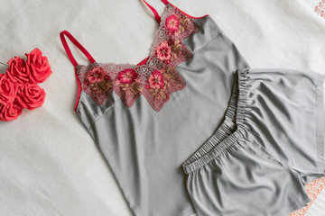 homemade silk pajamas lying on the bed without anyone. gray pajamas with red lace on a beige...