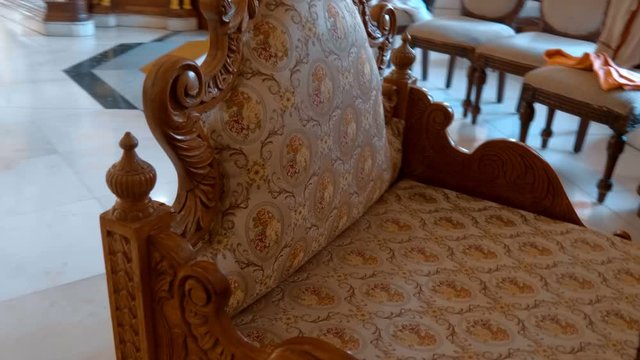 Traditional carved wooden armchair trimmed with yellow fabric with patterns in the Indian style. Shot in motion