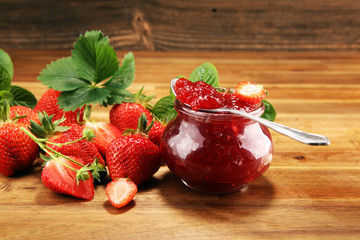 strawberry jam with fresh strawberries and mint. marmalade on spoon and jar on brown wood