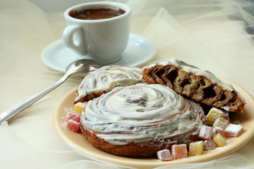 cinnamon puff and butter cream on a plate decorated with Turkish delight and a cup of coffee