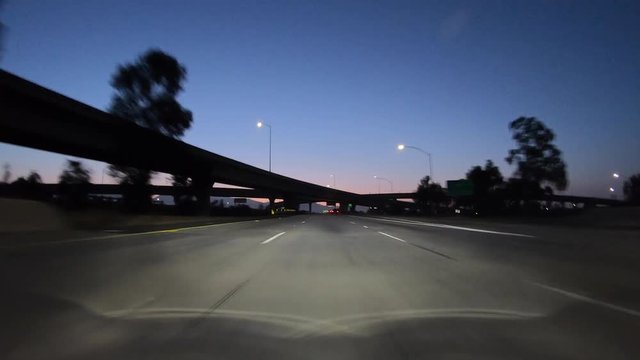Los Angeles dawn twilight driving on route 118 freeway below Interstate 5 interchange bridges in the San Fernando Valley area of Southern California.