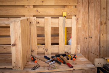 Wooden chair made by recycled pallet. carpenter corner with wooden table and tools. On background a pallet to work.