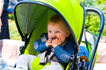 Little boy is sitting in pram with a smiling face and is happy