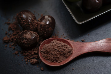 Chocolate round with cocoa powder wooden spoon and plate on top of Black rock stone plate