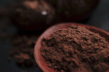 Chocolate round with cocoa powder wooden spoon and plate on top of Black rock stone plate