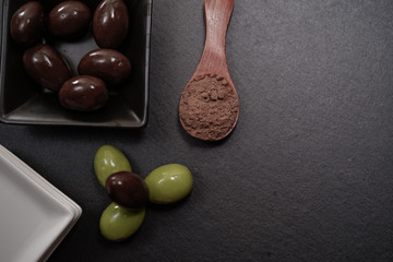 Chocolate round with cocoa powder wooden spoon and plate on top of Black rock stone plate