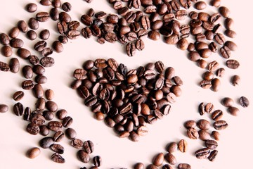 scattered on the table many coffee beans in the shape of a heart. lots scattered on the table roasted coffee beans in the shape of a heart, close up