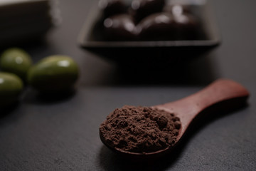 Chocolate round with cocoa powder wooden spoon and plate on top of Black rock stone plate