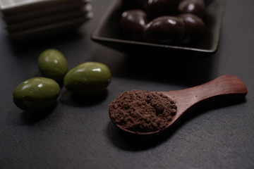 Chocolate round with cocoa powder wooden spoon and plate on top of Black rock stone plate