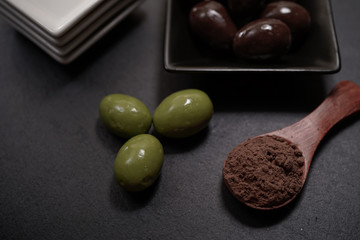 Chocolate round with cocoa powder wooden spoon and plate on top of Black rock stone plate