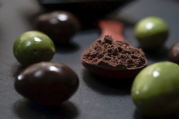 Chocolate round with cocoa powder wooden spoon and plate on top of Black rock stone plate