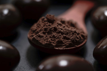 Chocolate round with cocoa powder wooden spoon and plate on top of Black rock stone plate