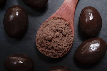 Chocolate round with cocoa powder wooden spoon and plate on top of Black rock stone plate