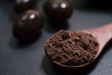 Chocolate round with cocoa powder wooden spoon and plate on top of Black rock stone plate