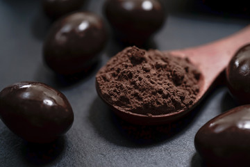 Chocolate round with cocoa powder wooden spoon and plate on top of Black rock stone plate