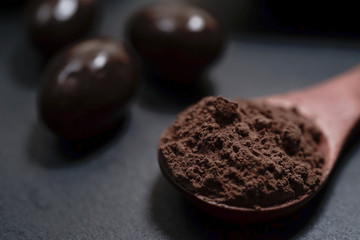 Chocolate round with cocoa powder wooden spoon and plate on top of Black rock stone plate