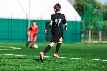 Boys in white and black sportswear plays  football on field, dribbles ball. Young soccer players with ball on green grass. Training, football, active lifestyle for kids concept 