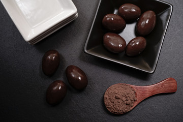 Chocolate round with cocoa powder wooden spoon and plate on top of Black rock stone plate