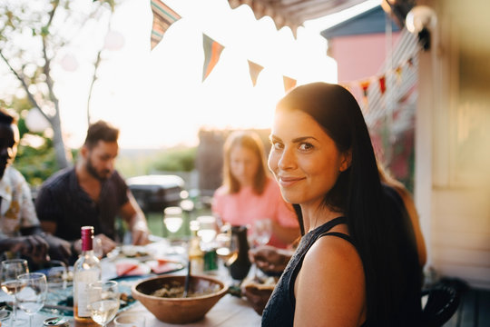 Portrait of smiling woman enjoying dinner party with friends at back yard