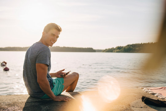 Portr&permil;tt av leende ung man p&Acirc; brygga under sommardag