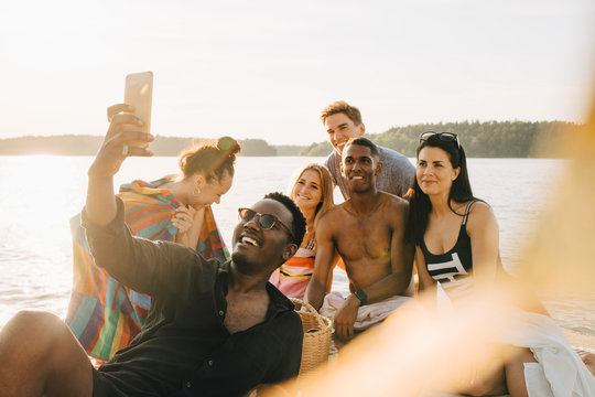 Man tar selfie med glada v&permil;nner p&Acirc; brygga vid vattnet