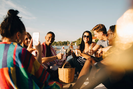 Kvinna tar bild p&Acirc; glada v&permil;nner under picknick p&Acirc; brygga