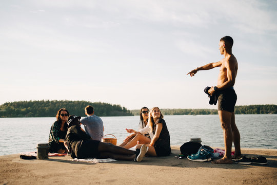 Man pekar och pratar med v&permil;nner som sitter p&Acirc; brygga vid vattnet