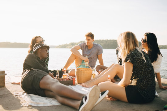 Grupp v&permil;nner dricker och umg&Acirc;s under picknick p&Acirc; brygga
