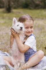 Adorable little girl holding a Westie puppy
