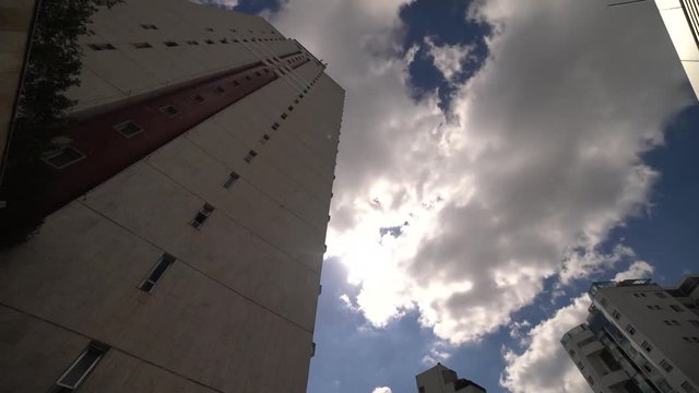 Time lapse of cloudy sky and a tall building in a sunny day