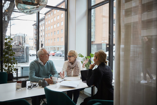 Retired Couple Talking While Sitting With Real Estate Agent In Office