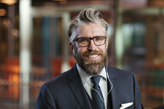 Portr&permil;tt av leende man med kostym och h&circ;rlurar p&Acirc; kontor
