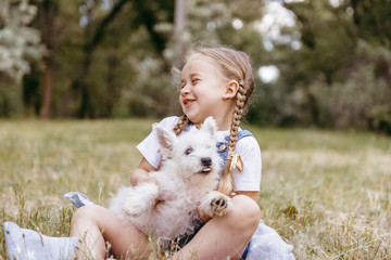 Adorable little girl holding a Westie puppy
