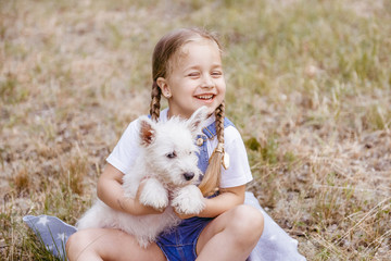 Adorable little girl holding a Westie puppy