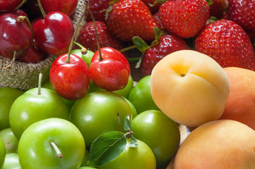 close up summer fruits background, green plum, red cherry, strawberry, apricot on. top view, copy space for text, selective focus