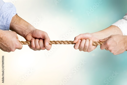 Business people pulling rope in opposite directions at office