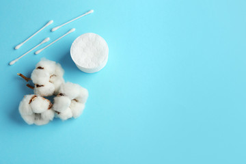 Flat lay composition with cotton pads, swabs and flowers on color background. Space for text