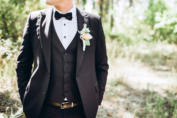 the groom in a suit straightens his tie bubochku. boutonniere on the lapel of his jacket. young man...