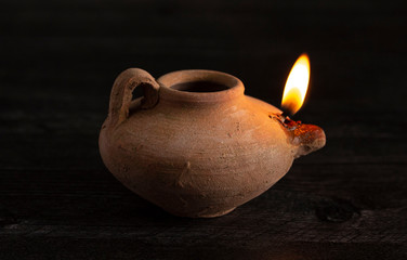 A Lit Handmade Oil Lamp from the Middle East on a Dark Table