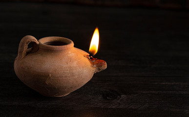 A Lit Handmade Oil Lamp from the Middle East on a Dark Table