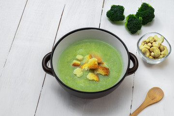 Vegan broccoli soup with cashew on white wooden background, copy space