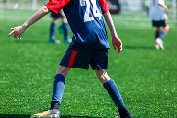 Boys at blue white sportswear run, dribble, attack on football field. Young soccer players with ball on green grass. Training, football, active lifestyle for kids
