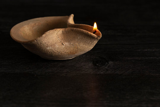 A Lit Handmade Oil Lamp from the Middle East on a Dark Table